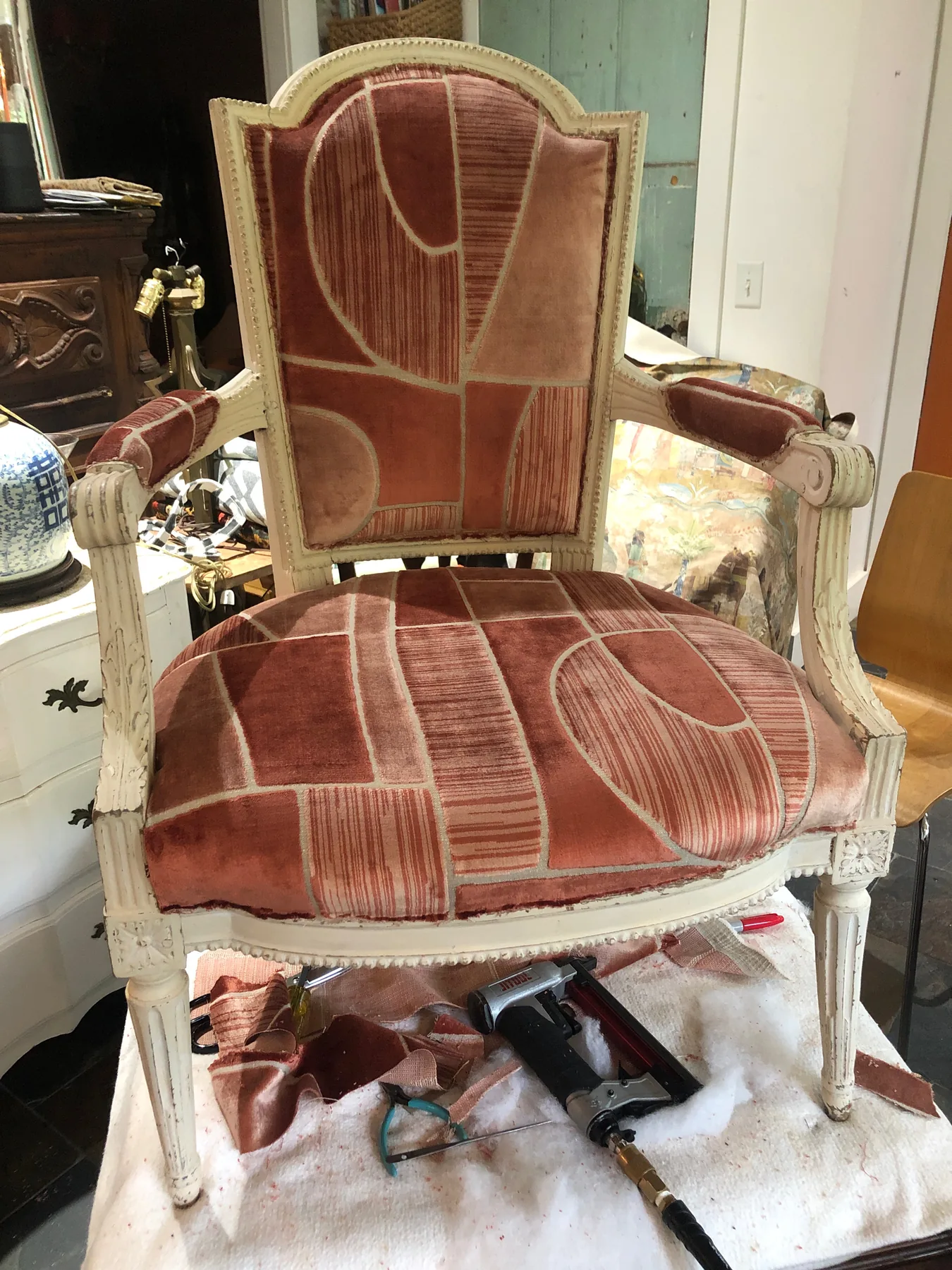 Front view of an antique chair reupholstered in rose and cream fabric.