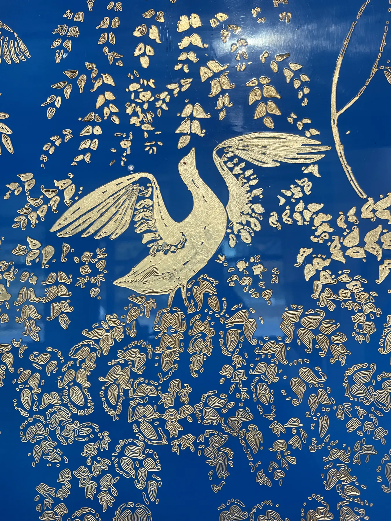 Gold birds and foliage arranged across a rich blue decorative surface.