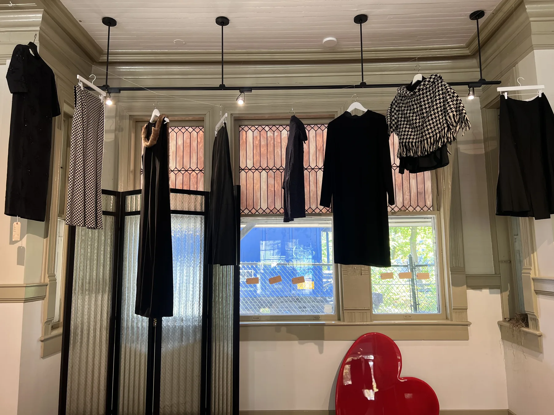 Garments by Junya Watanabe and Yohji Yamamoto suspended across a gallery window.