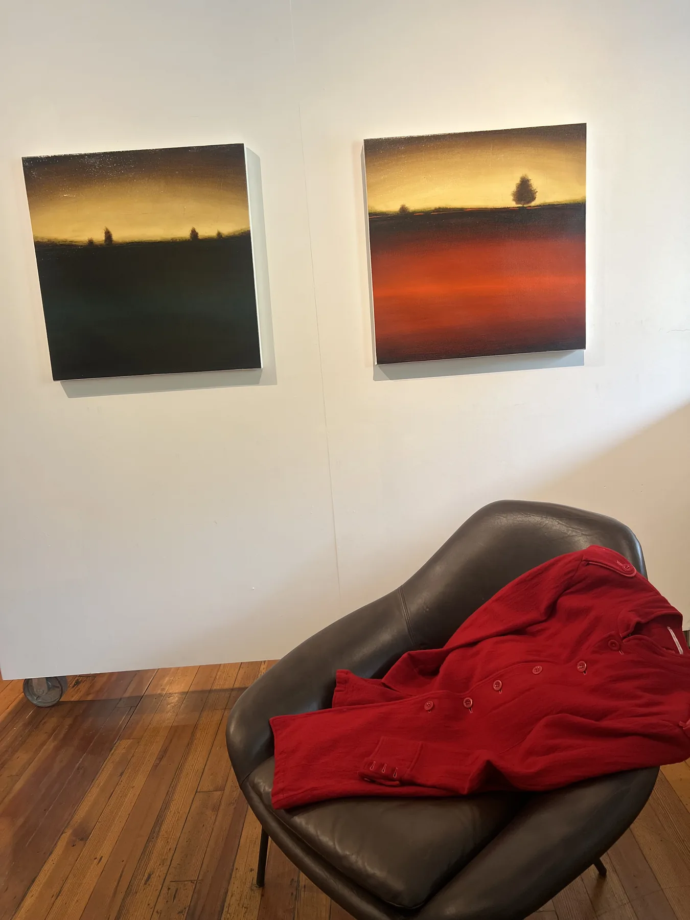 Two La Vista paintings by Ivan "Shie" Moreno installed above a red Yohji Yamamoto coat.